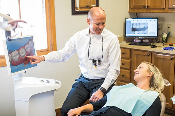 Dr. Thad Twiss showing a patient the CEREC machine to produce same-day crowns in Edwards, CO