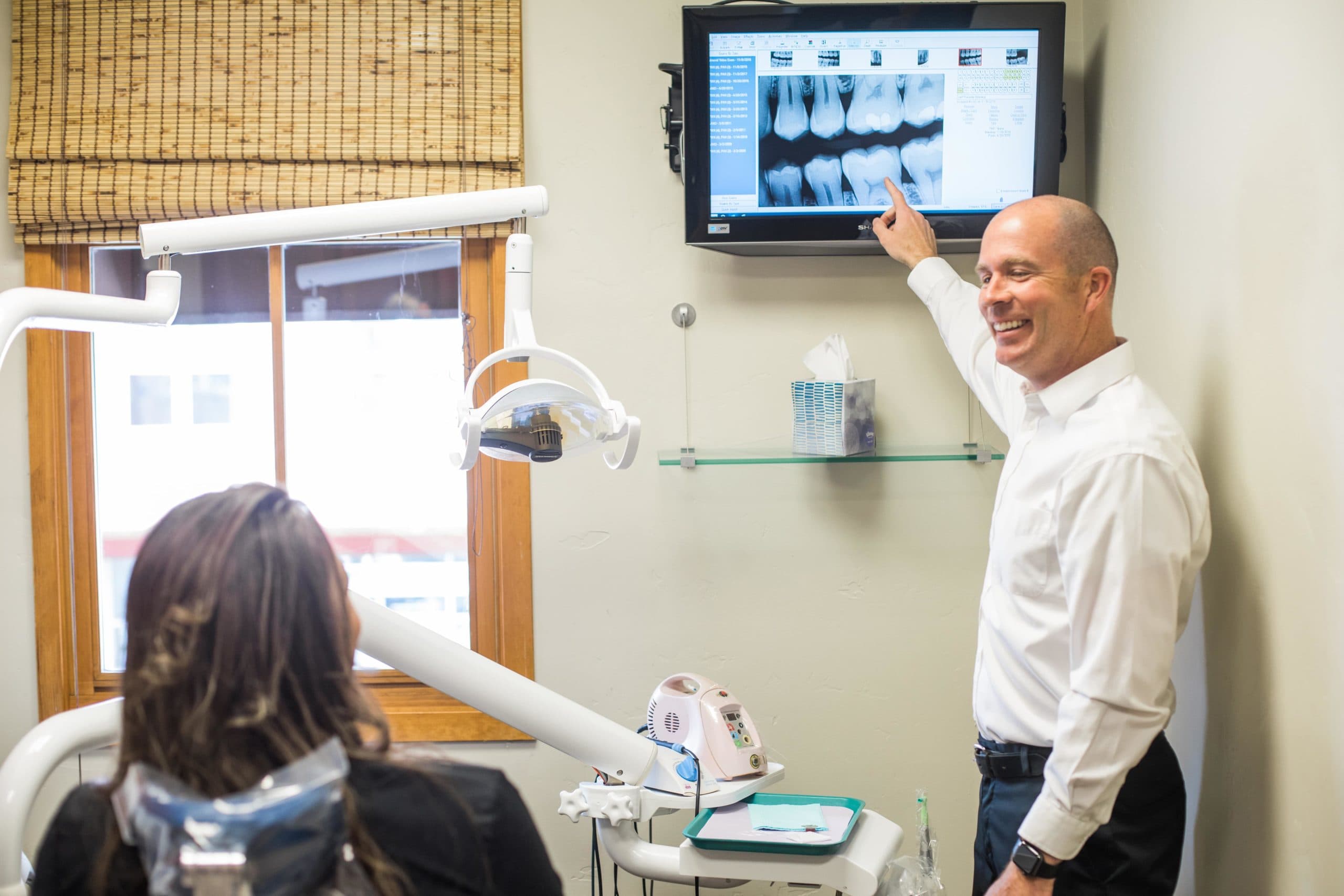 Dr. Thad Twiss pointing to x-ray in front of dental patient.